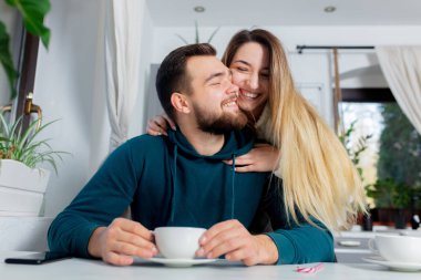 Genç evli çift mutfakta kahve içiyor.