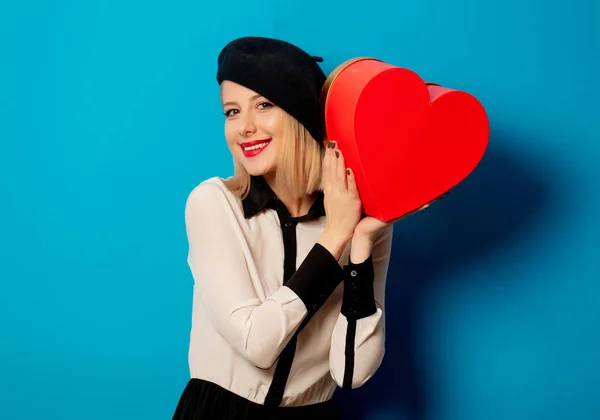 Beautiful french woman in beret with heart shape gift box — Stock Photo, Image