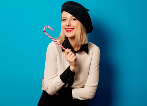 Bella donna francese in berretto con caramelle lecca lecca sul retro blu — Foto Stock