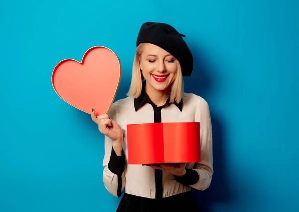 Beautiful french woman in beret with heart shape gift box — Stock Photo, Image