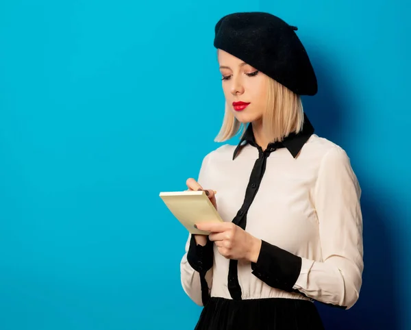 Hermosa mujer francesa en boina sostiene cuaderno con lápiz en bl — Foto de Stock