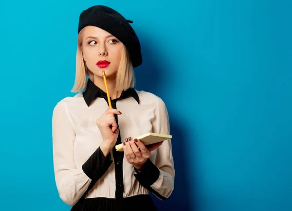 Mooie franse vrouw in baret houdt notebook met potlood op bl — Stockfoto