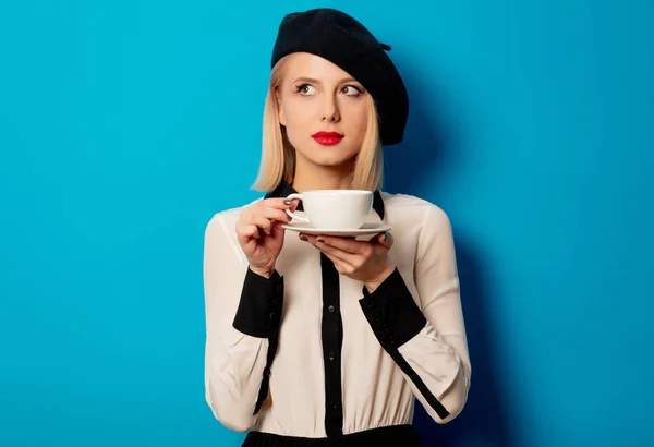 Hermosa mujer francesa en boina sostiene taza blanca de café — Foto de Stock