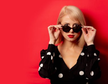 Kırmızı arka planda güneş gözlüklü güzel kadın.