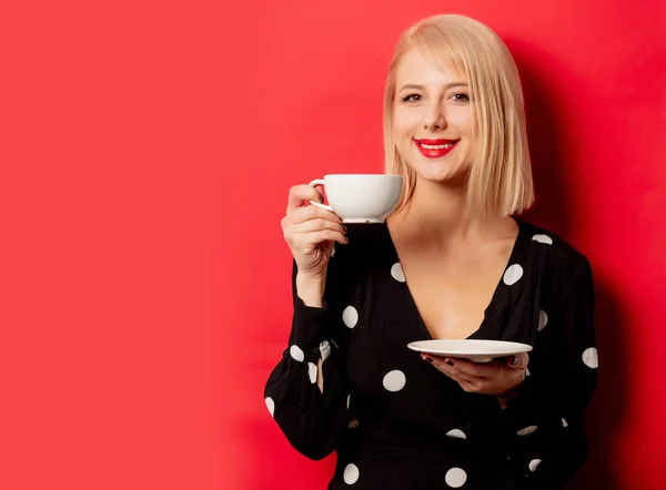 Bela mulher francesa detém xícara de café no fundo vermelho — Fotografia de Stock