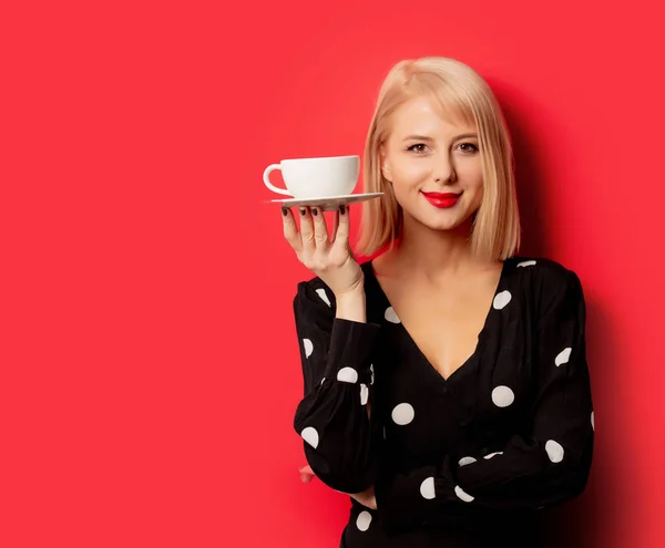 Bela mulher francesa detém xícara de café no fundo vermelho — Fotografia de Stock