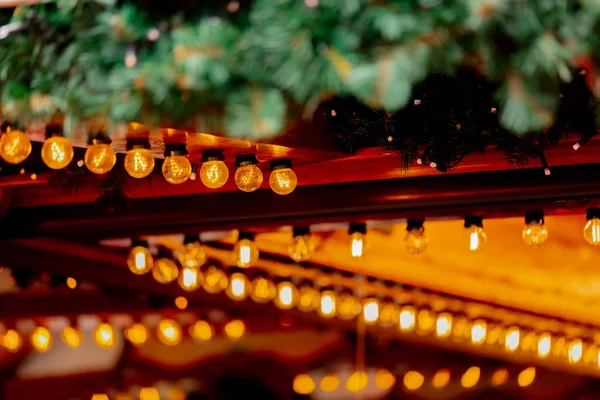 Fairy luces decoración de casas de madera en el mercado de Navidad en —  Fotos de Stock