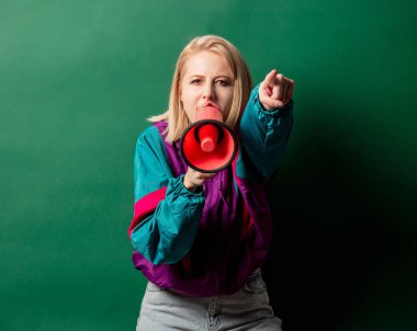 90 'ların tarzı punk ceketli, hoparlörlü, yeşil arkası olan bir kadın.