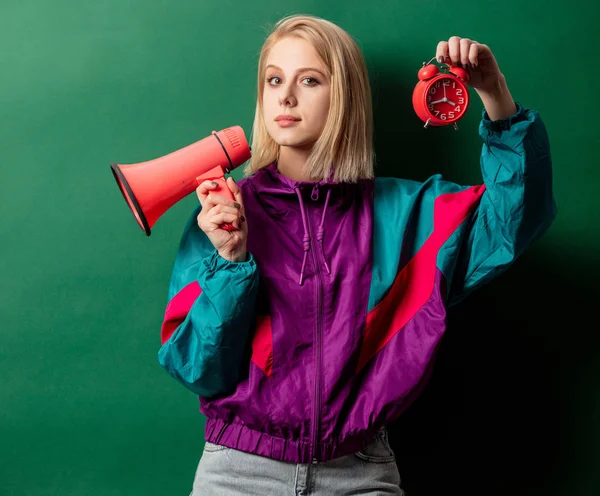 Woman in 90s style punk jacket with loudspeaker and alarm clock — Stock Photo, Image