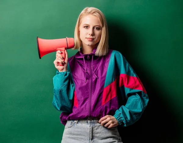 Woman in 90s style punk jacket with loudspeaker on green backgro — Stock Photo, Image
