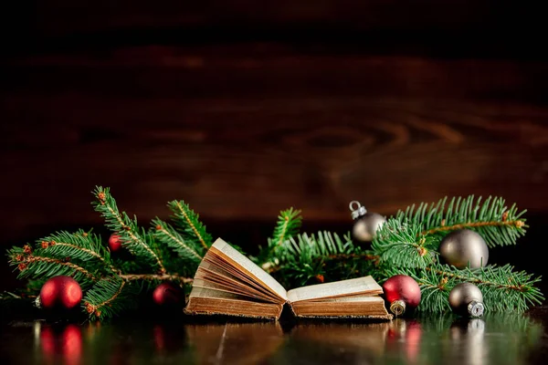 Old book and Christmas baubles on wooden table — Stock Photo, Image