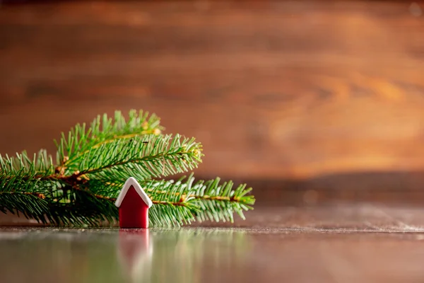 Piccolo giocattolo della casa e ramo dell'albero di Natale sul tavolo di legno — Foto Stock