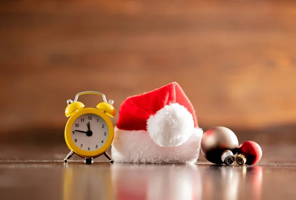 Weihnachtsmann-Hut und Wecker auf Holztisch und Hintergrund — Stockfoto