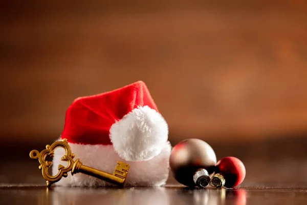 Cappello e chiave di Babbo Natale con palline sul tavolo di legno — Foto Stock
