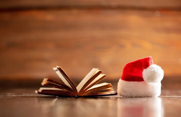 Boże Narodzenie kapelusz i otwarta książka na drewnianym stole — Zdjęcie stockowe
