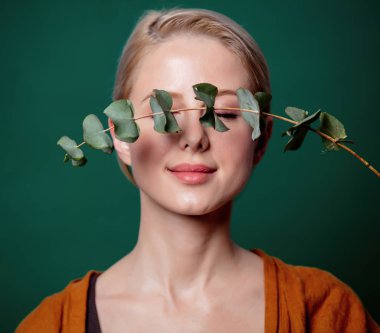 Kadın yeşil arka planda okaliptüs dalı tutuyor