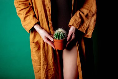 Kadın kaktüsü ayak hizasında tutuyor.