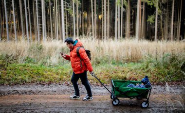 Genç baba ormanda bir arabayla bir çocukla yürüyor.