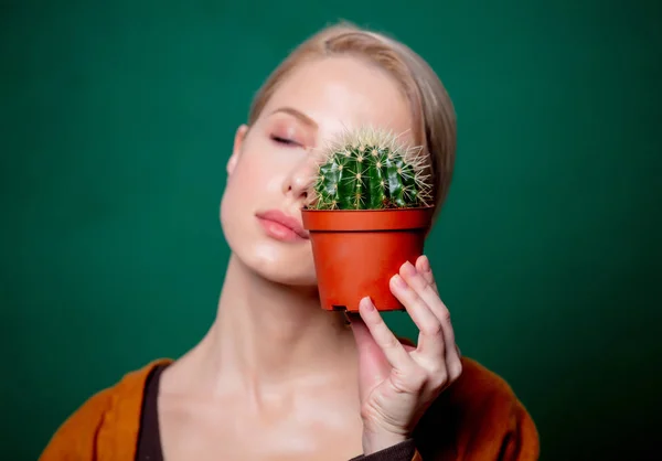 Kvinna håller kaktus i handen nära ett ansikte på grön bakgrund — Stockfoto