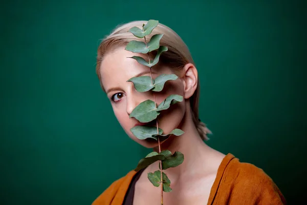 Жінка тримає гілку евкаліпта на зеленому тлі — стокове фото