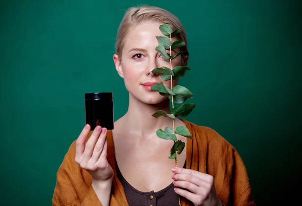 Woman holds eucalyptus branch and jar on green background — ストック写真