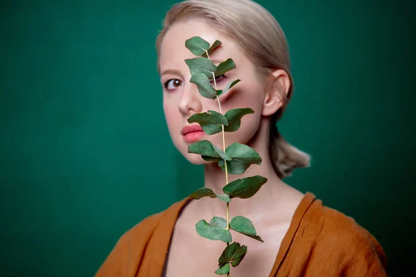 Žena drží eukalyptovou větev na zeleném pozadí — Stock fotografie