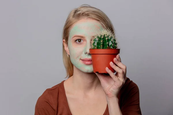 Beautiful blond girl with green mask and cactus — Stock Photo, Image