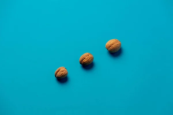 Tres nueces sobre una superficie azul — Foto de Stock