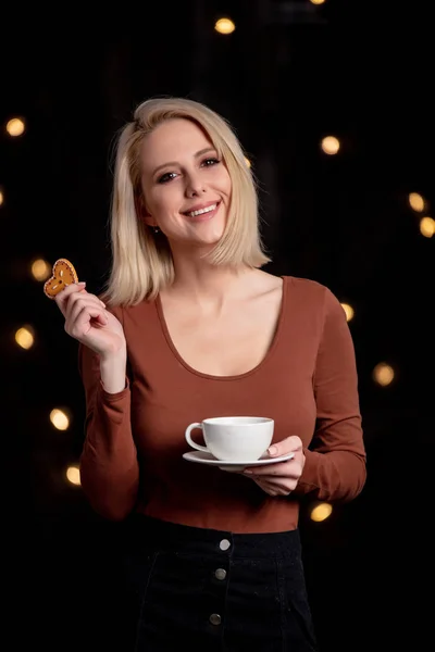 Blond meisje met kopje koffie en peperkoekje op backgro — Stockfoto