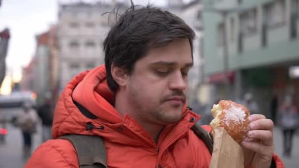 Άνθρωπος Τρώει Παραδοσιακό Πολωνικό Ντόνατ Στο Δρόμο Της Πόλης — Αρχείο Βίντεο