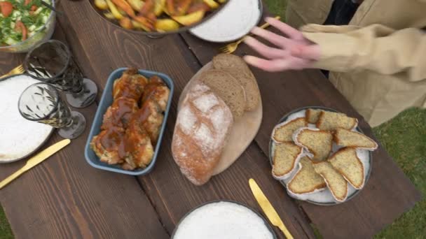 Mujer pone comida en una mesa en el patio trasero — Vídeos de Stock