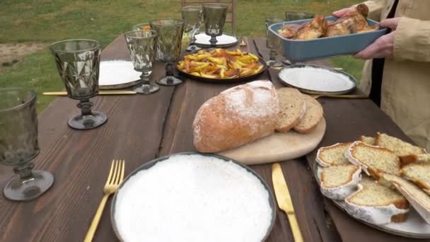 Vrouw legt eten op een tafel in de achtertuin — Stockvideo