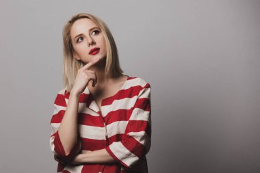 Gri arka planda çizgili ceketli sarışın kadın şaşırdı.