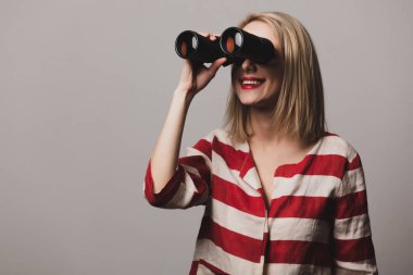 Güzel kız gri arka planda dürbün tutuyor.