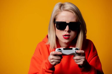 Güneş gözlüklü kız bilgisayar oyununda joystick ile oynuyor.