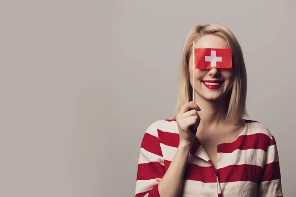 Ragazza tiene Svizzera bandiera su sfondo grigio — Foto Stock