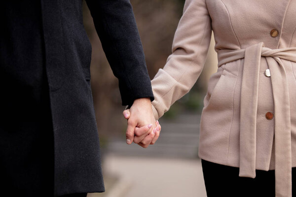 молодая пара, держащаяся за руки на улице
