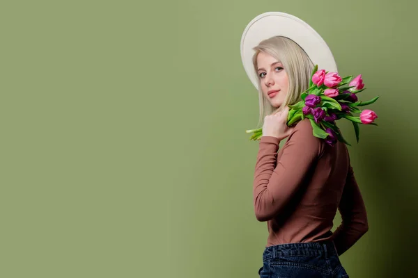 Mooie vrouw in een hoed met tulpen boeket — Stockfoto