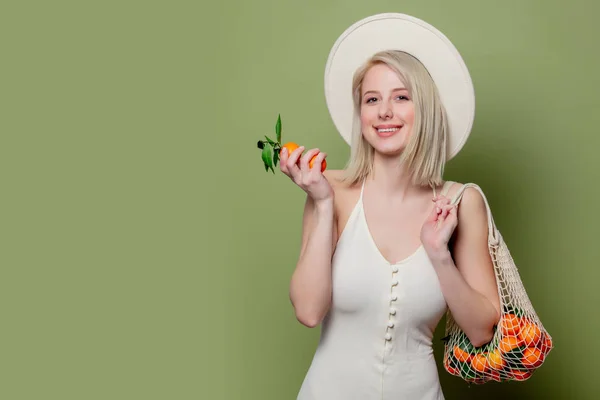 Schöne Frau mit Hut und weißem Kleid mit Mandarinen — Stockfoto