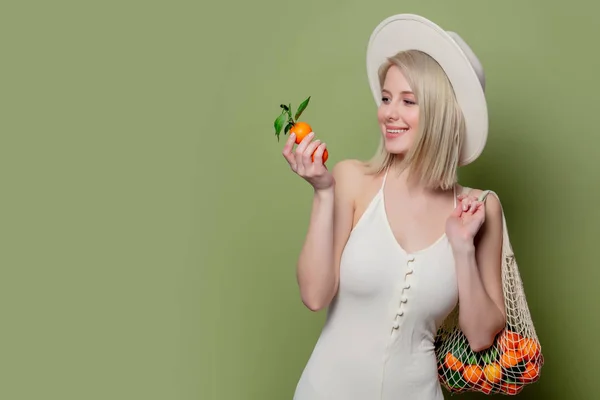 Beautiful woman in a hat and white dress with a mandarins — Stock Photo, Image