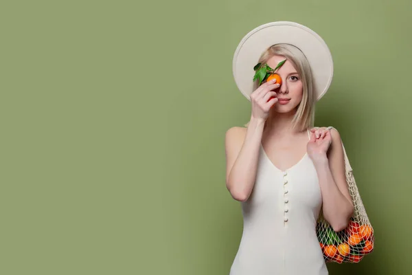 Vacker kvinna i hatt och vit klänning med en mandariner — Stockfoto