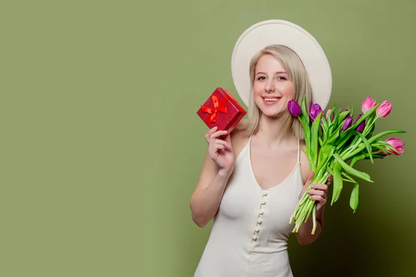 Красивая блондинка с тюльпанами и подарочной коробкой — стоковое фото