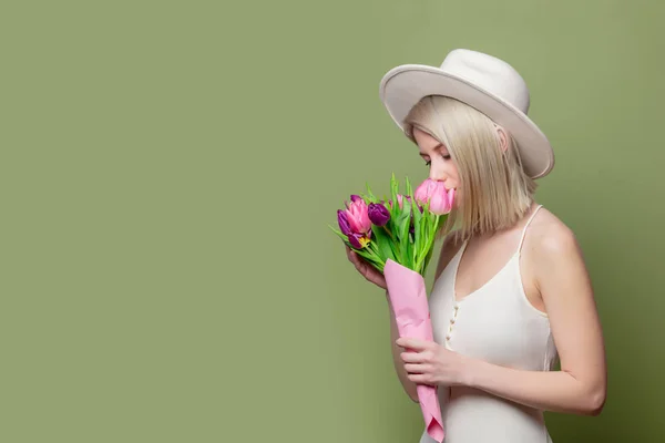 Schöne blonde Mädchen mit weißem Hut und Kleid mit Tulpen — Stockfoto