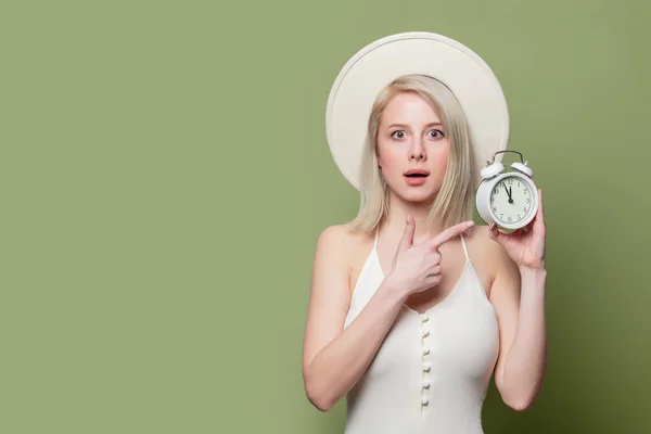 Menina loira bonita em chapéu branco e vestido com despertador — Fotografia de Stock