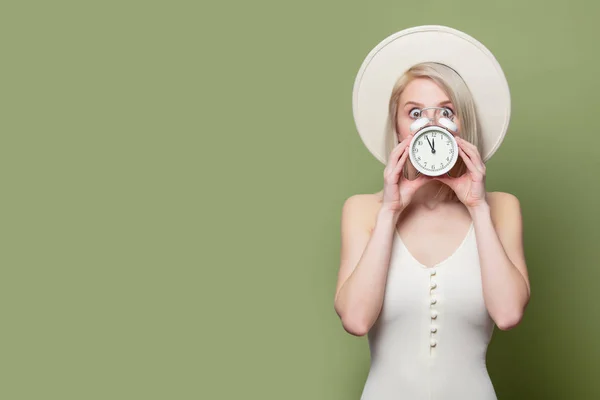 Όμορφη ξανθιά κοπέλα σε λευκό καπέλο και φόρεμα με ξυπνητήρι — Φωτογραφία Αρχείου