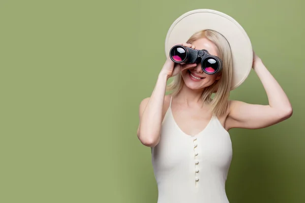 Belle fille blonde dans un chapeau blanc et robe avec des jumelles — Photo