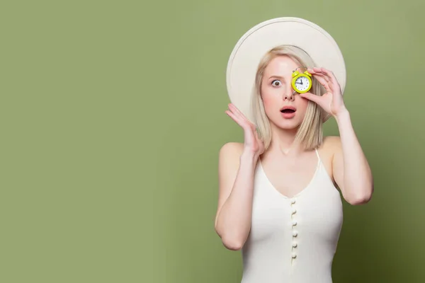 Bella ragazza bionda in un cappello bianco e vestito con piccola sveglia — Foto Stock