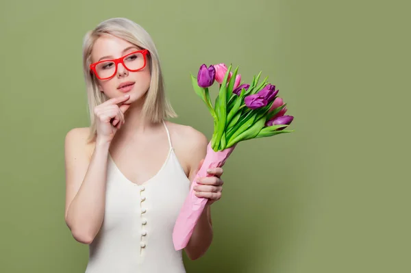 Překvapená blondýna dívka s tulipány na zeleném pozadí — Stock fotografie