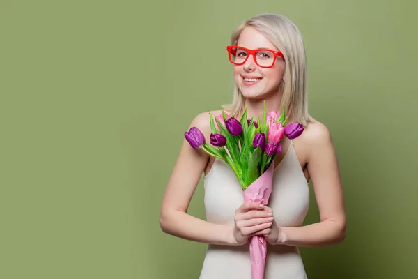 Menina loira surpreso com tulipas no fundo verde — Fotografia de Stock
