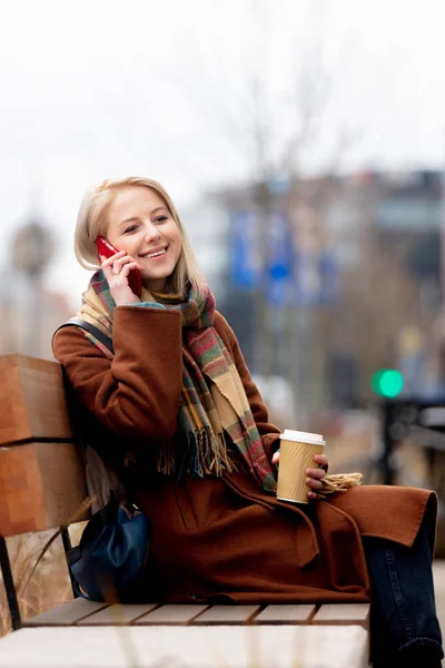Piękna blondynka z filiżanką kawy i telefonem komórkowym — Zdjęcie stockowe